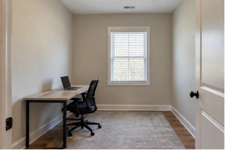 Plain spare-room home office before an illustrative AI redesign